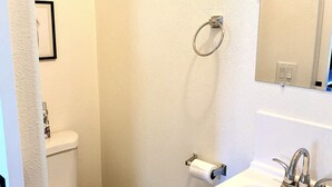 Un baño con inodoro, lavamanos, ducha y espejo.