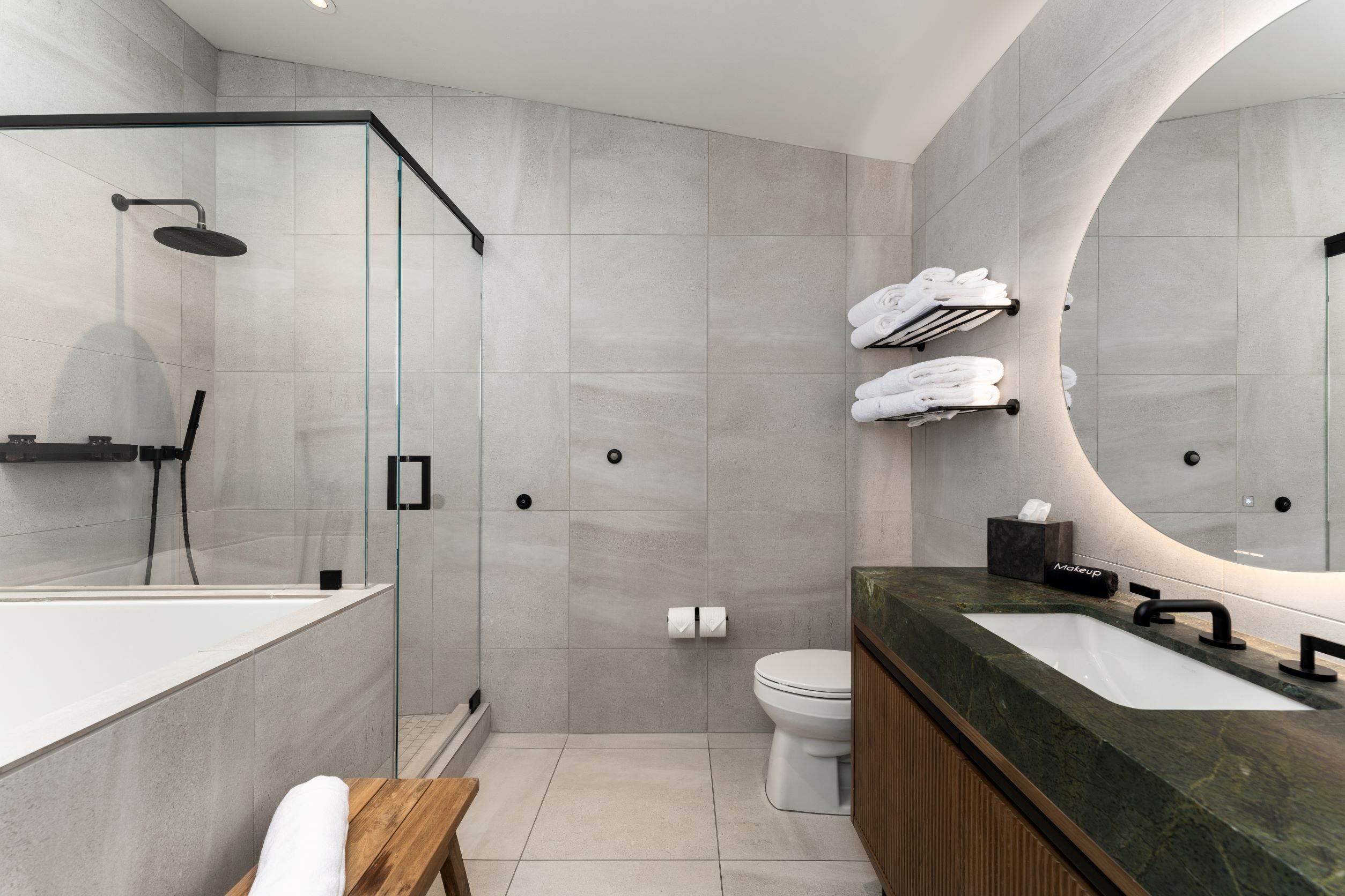 A modern bathroom with a glass-enclosed shower, a large mirror, and a vanity with a marble countertop.