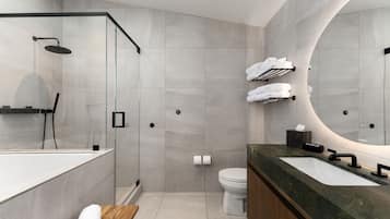 A modern bathroom with a glass-enclosed shower, a large mirror, and a vanity with a marble countertop.
