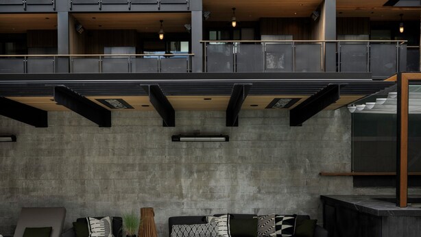 A modern multi-story building with a pool area featuring outdoor seating and a fire pit.