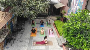 A courtyard with six people on yoga mats, a tiled floor, and surrounding greenery. - Hostel Nucapacha (Guayaquil)
