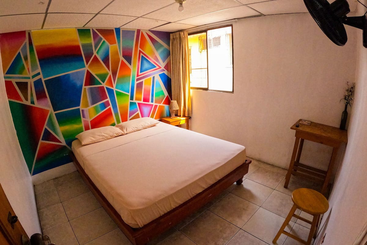 A room with a bed, a desk, a chair, a lamp, and a window.