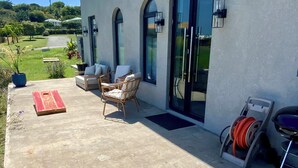 Un área de patio con mobiliario exterior, un tapete rojo y un carretel de manguera.