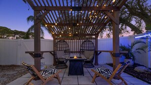 A patio area with a pergola, outdoor seating, and a fire feature. - Tranquil Tropics| Heated Pool, Games, 10 to Beach (Largo)