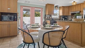 A kitchen with wooden cabinets, a microwave, a coffee maker, and a dining table with chairs. - Tranquil Tropics| Heated Pool, Games, 10 to Beach (Largo)