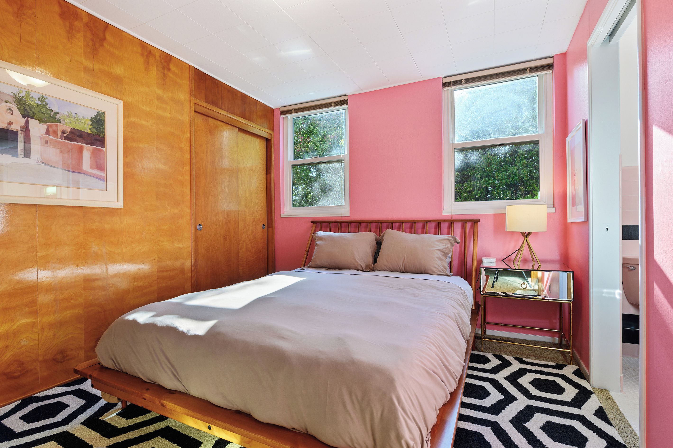 Un dormitorio con una cama, una mesita de noche, una ventana y una puerta.