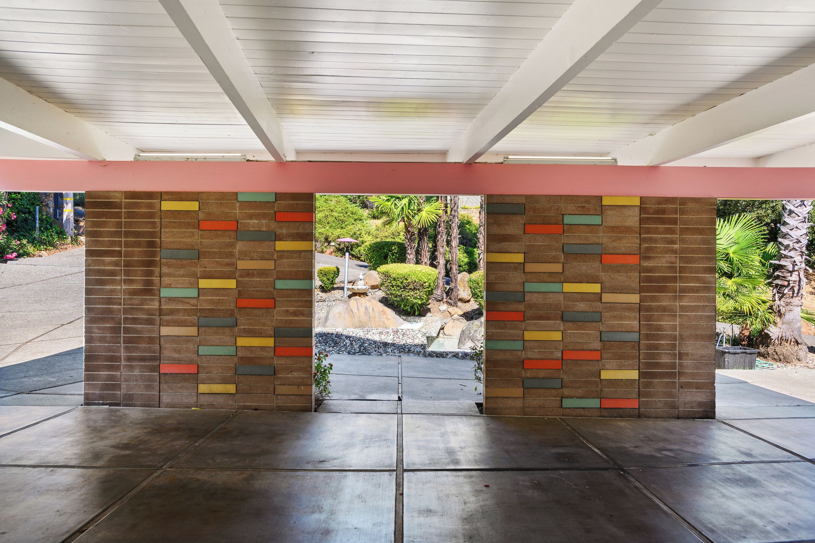 A covered entrance with a brick wall featuring a colorful pattern.