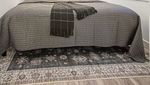 Ein Schlafzimmer mit einem Bett, einem Deckenventilator, einem Fenster mit Jalousie und einer Wandklimaanlage.