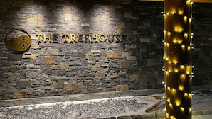 A stone wall with the text "THE TREHOUSE" and a circular logo with a mountain and a house.