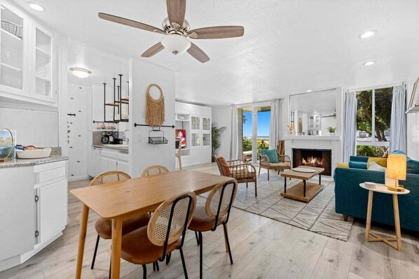 A spacious living area with a wooden dining table, chairs, a sofa, and a fireplace.