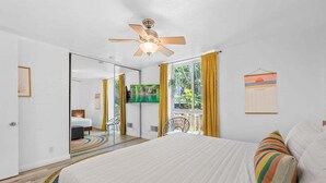 A bedroom with a bed, a ceiling fan, a TV, and a window with curtains. - Amazing Ocean Views-Walk Out Beach Access - Spacious living room area- North Coast Village G35 (Oceanside)