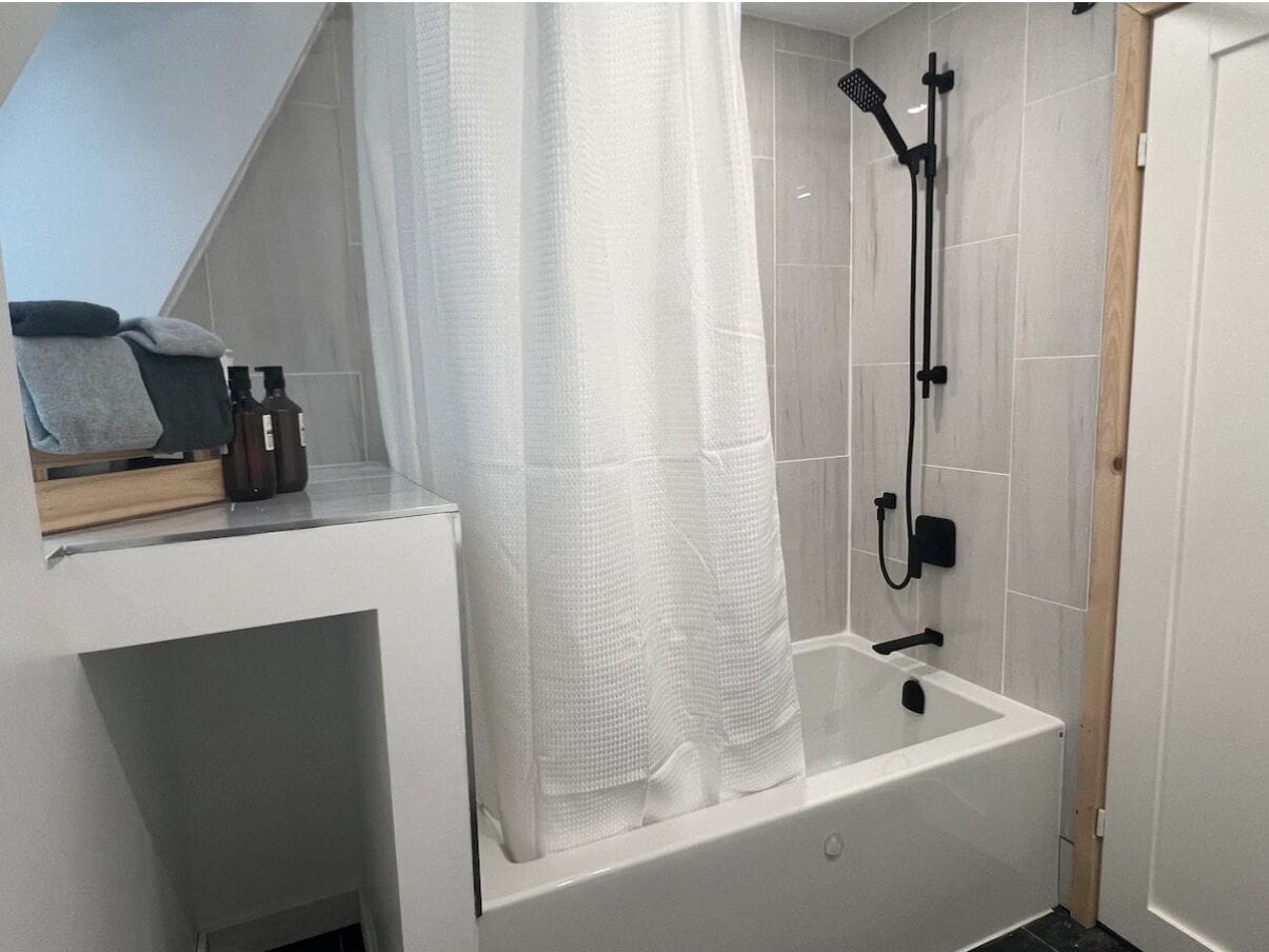 Une salle de bain moderne équipée d’une baignoire, d’une douche et d’un porte-serviettes.