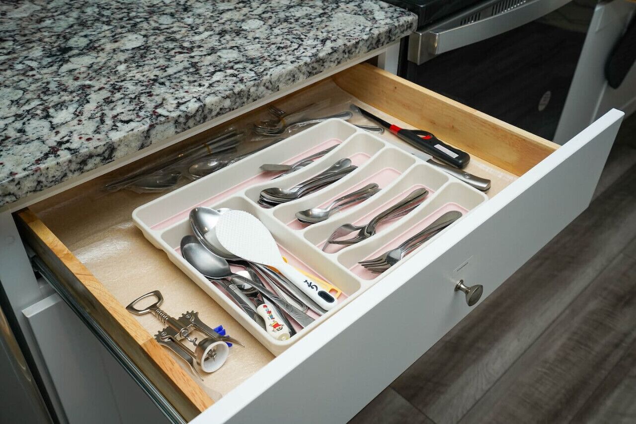 A kitchen drawer with utensils and cookware.
