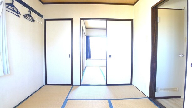 Una habitación con suelo de tatami, puerta corredera y perchero en la pared.