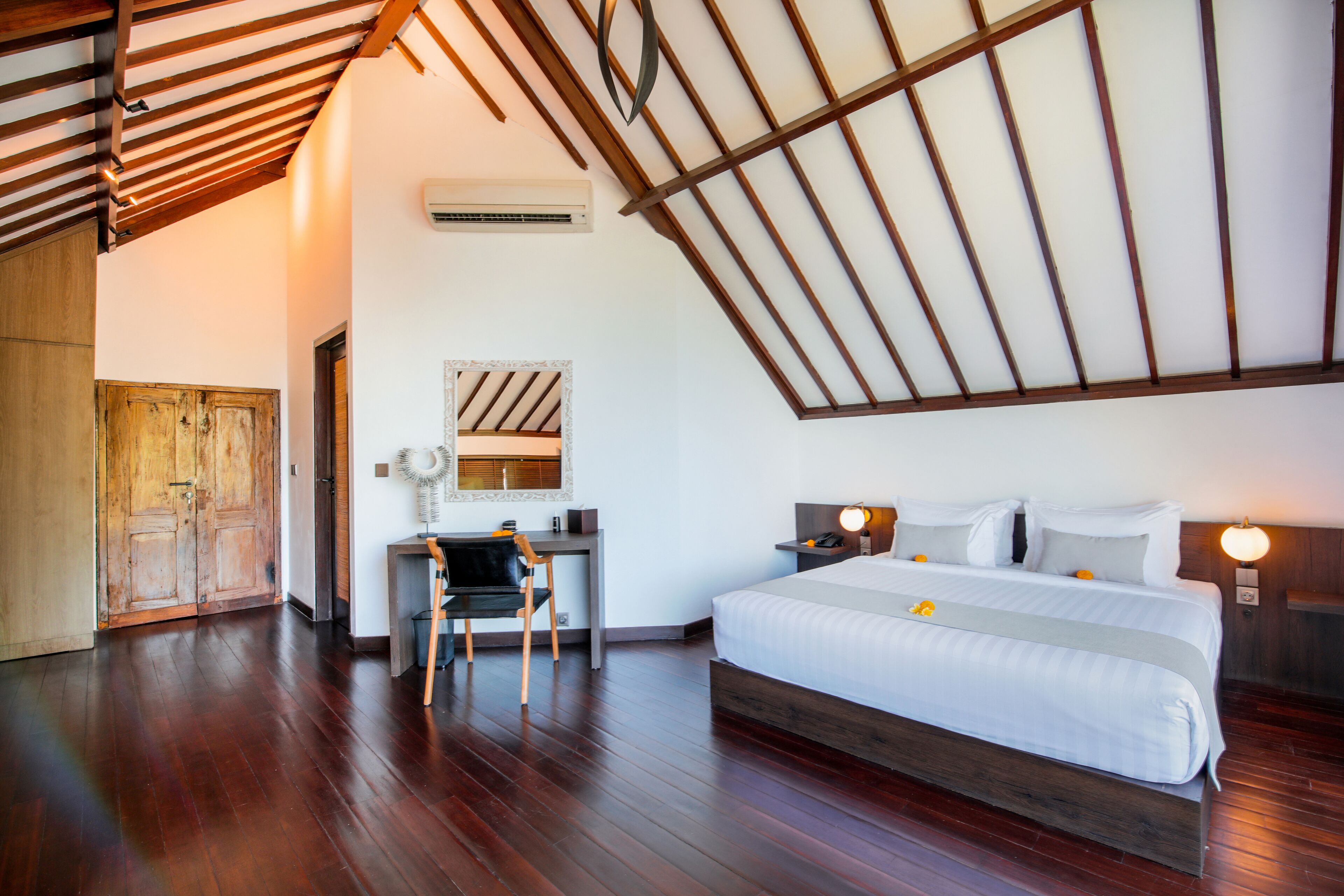 A bedroom with a wooden ceiling, a bed, a desk, and a chair.