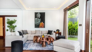 En moderne stue med en modulsofa, et træbord og en stor Buddha-figur på væggen.
