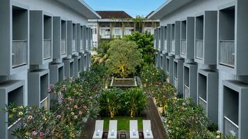A modern hotel with a central pool, lounge chairs, and a garden view.