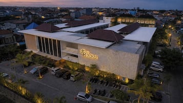 A hotel with a modern design, featuring a prominent 'The Rooms' sign, multiple parking spaces, and a surrounding urban environment.