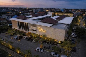 Een hotel met een modern design, met een opvallend bord 'The Rooms', meerdere parkeerplaatsen en een omliggende stedelijke omgeving.