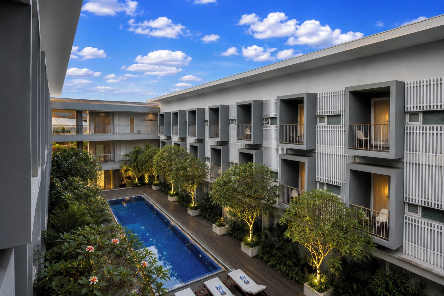Un hôtel moderne doté d’une piscine sur le toit, de nombreux balcons et d’une végétation luxuriante.