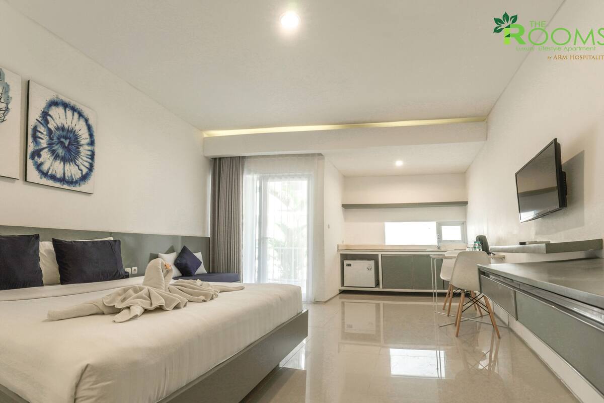 Une chambre d’hôtel moderne, dotée d’un grand lit, d’un bureau et d’une télévision.