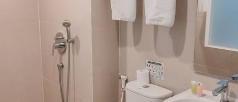 Une salle de bain comprenant des toilettes, un bidet, une douche et un lavabo.
