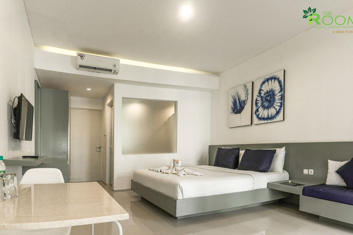 Een moderne hotelkamer met een bed, een slaapbank, een eettafel en kunstwerken aan de wanden.