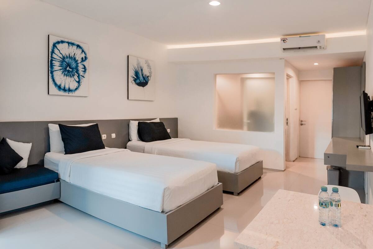 Une chambre d’hôtel moderne équipée de deux lits, d’un bureau et d’une salle de bain.