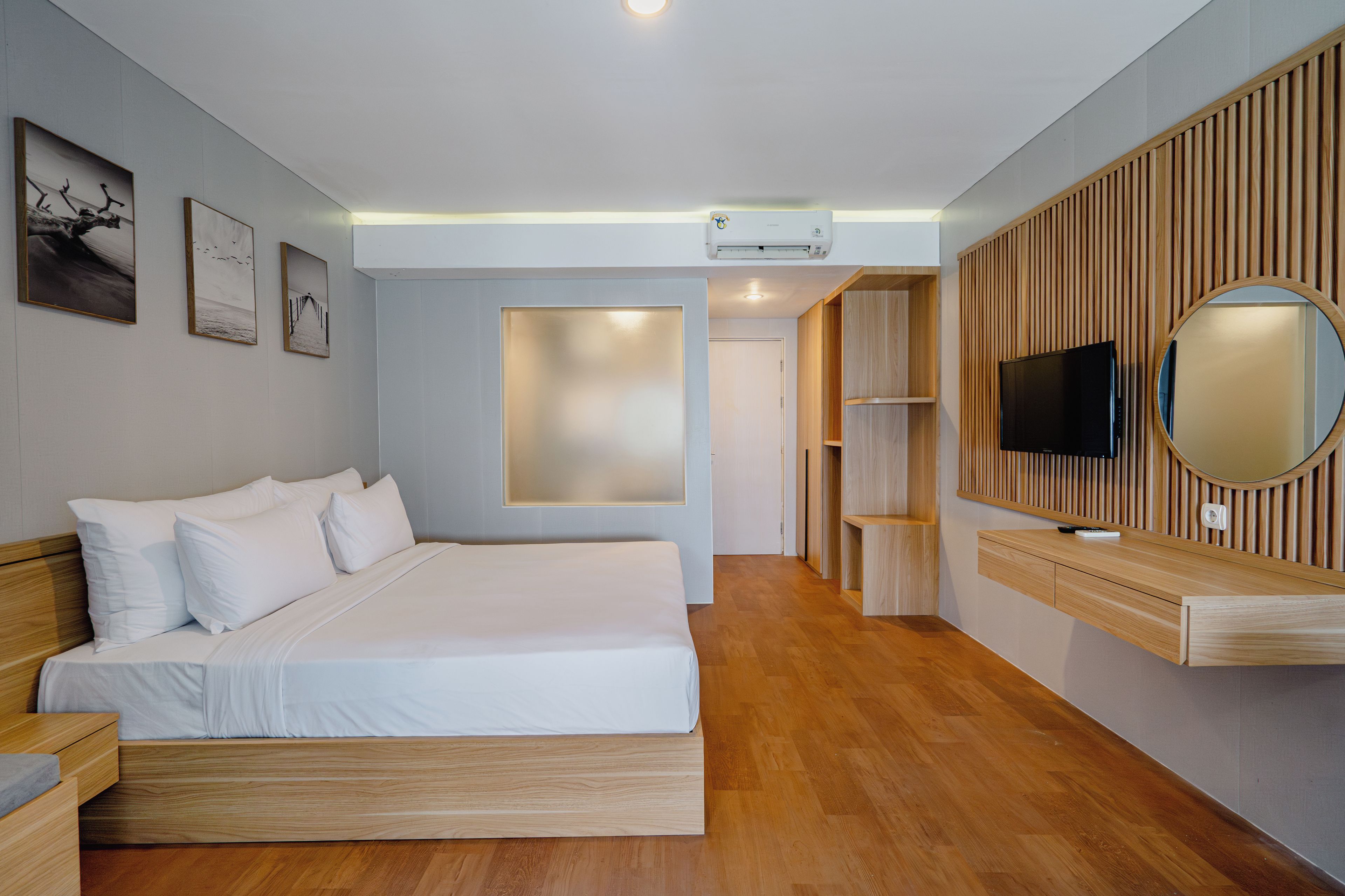 A modern bedroom with a wooden bed, a flat-screen TV, and a large mirror on the wall.