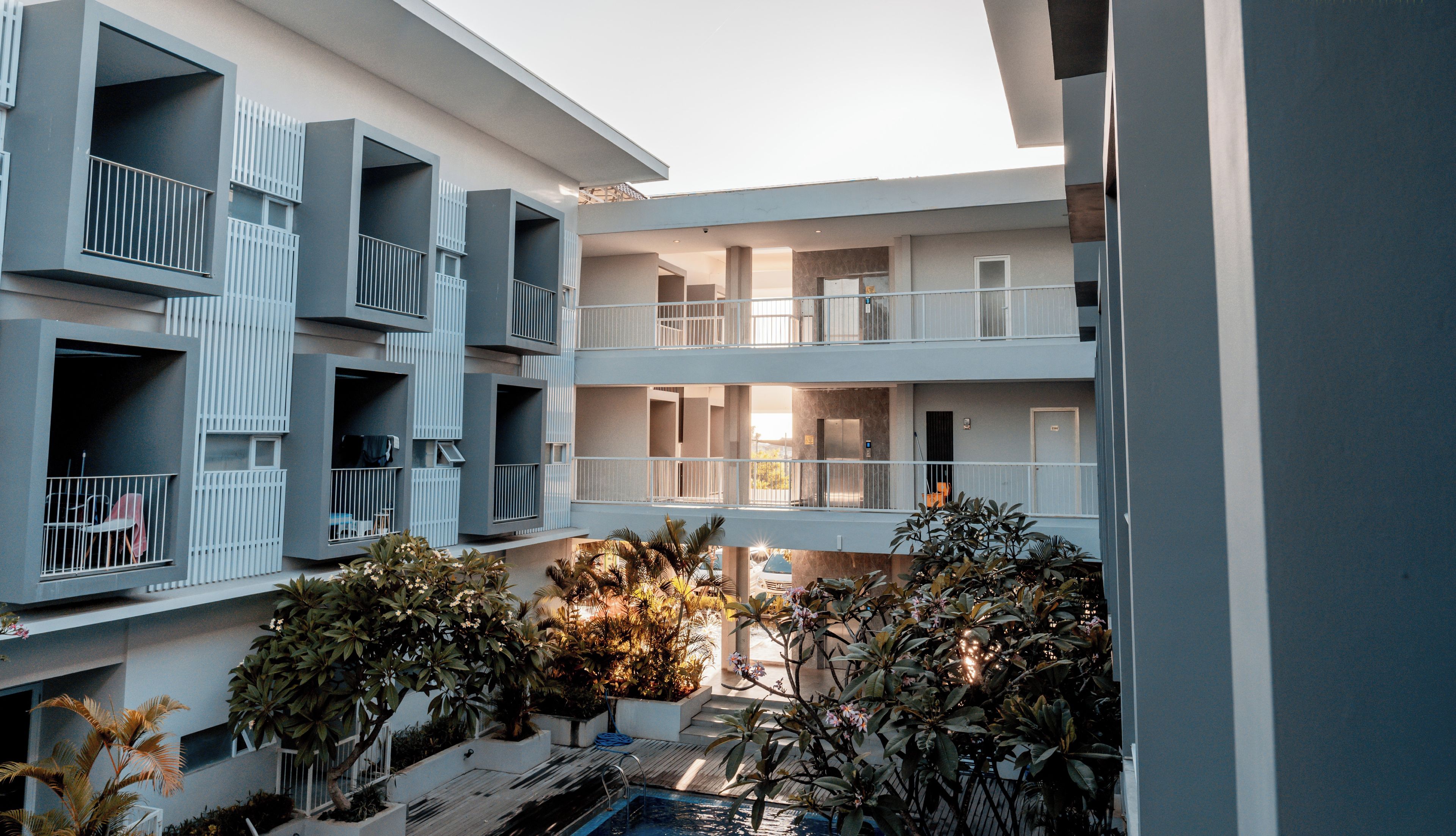 Um edifício residencial com vários andares, varandas, pátio e piscina.