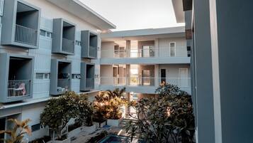 Um edifício residencial com vários andares, varandas, pátio e piscina.