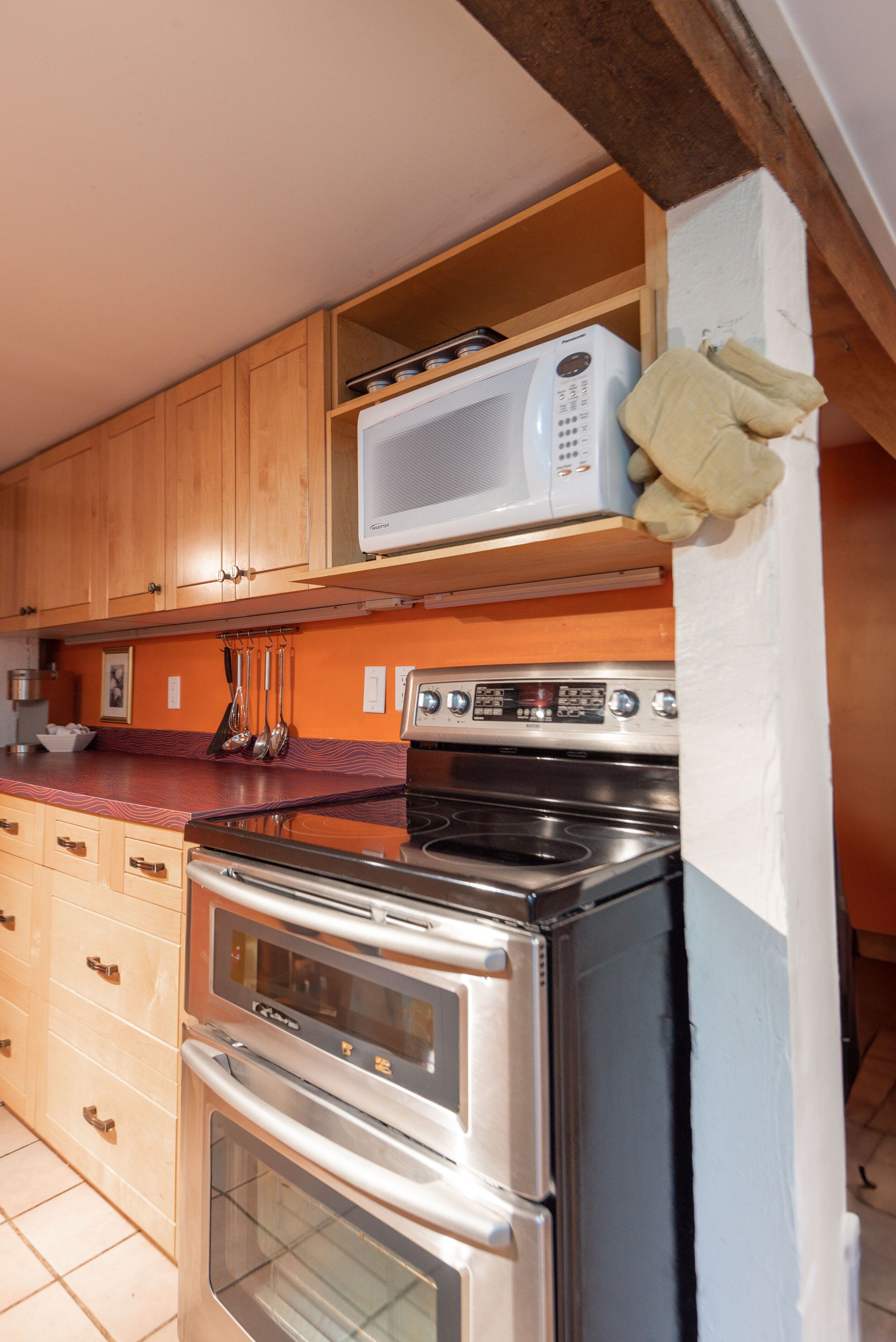 A kitchen with wooden cabinets, a microwave, a stove, and a refrigerator.