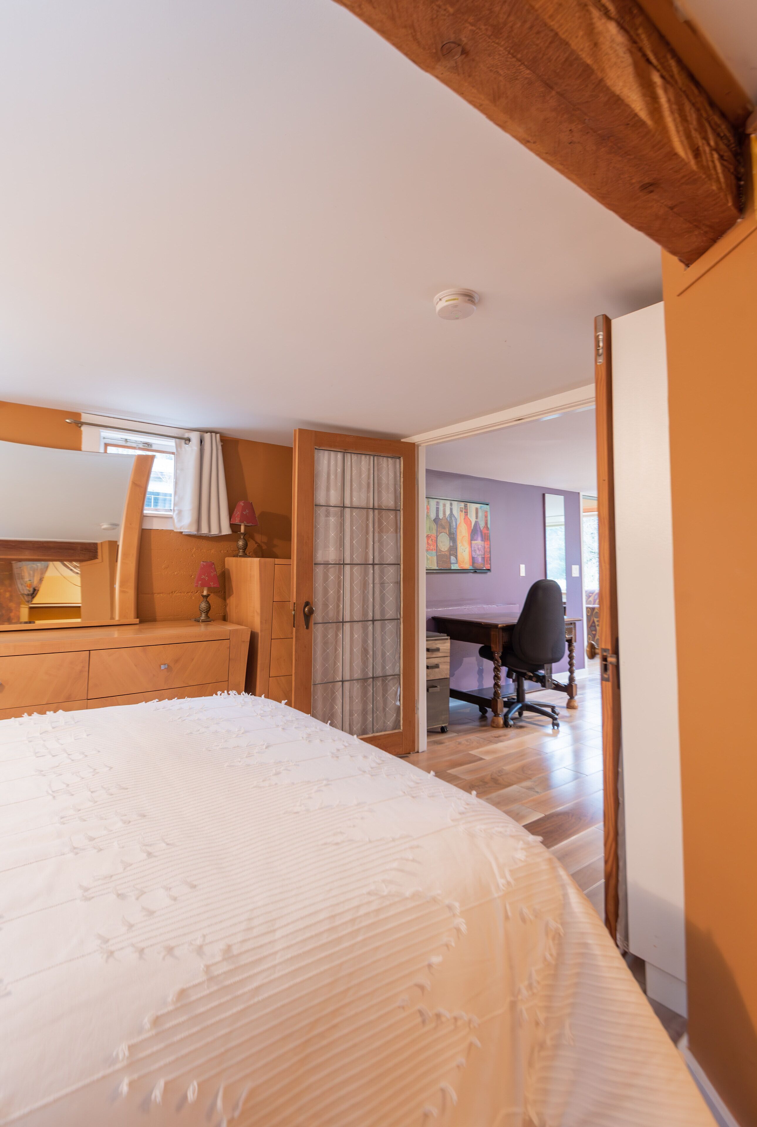 Un dormitorio con cama, cómoda, escritorio y silla.