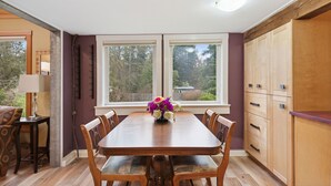 Een eethoek met een houten tafel, stoelen en een bloevas.