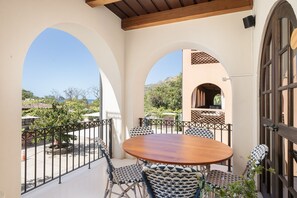 A patio with a round table and chairs, surrounded by arches and a view of the landscape.