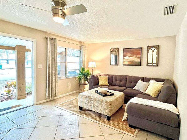 A living room with a sofa, ottoman, and a ceiling fan. - The Floridian, 5 beds, Sleeps 7, Ping Pong Table (Mount Dora)
