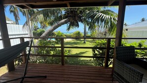 A wooden deck with a hammock and wicker furniture, overlooking a well-maintained lawn and palm trees. - Moemiti (Moorea-Maiao)