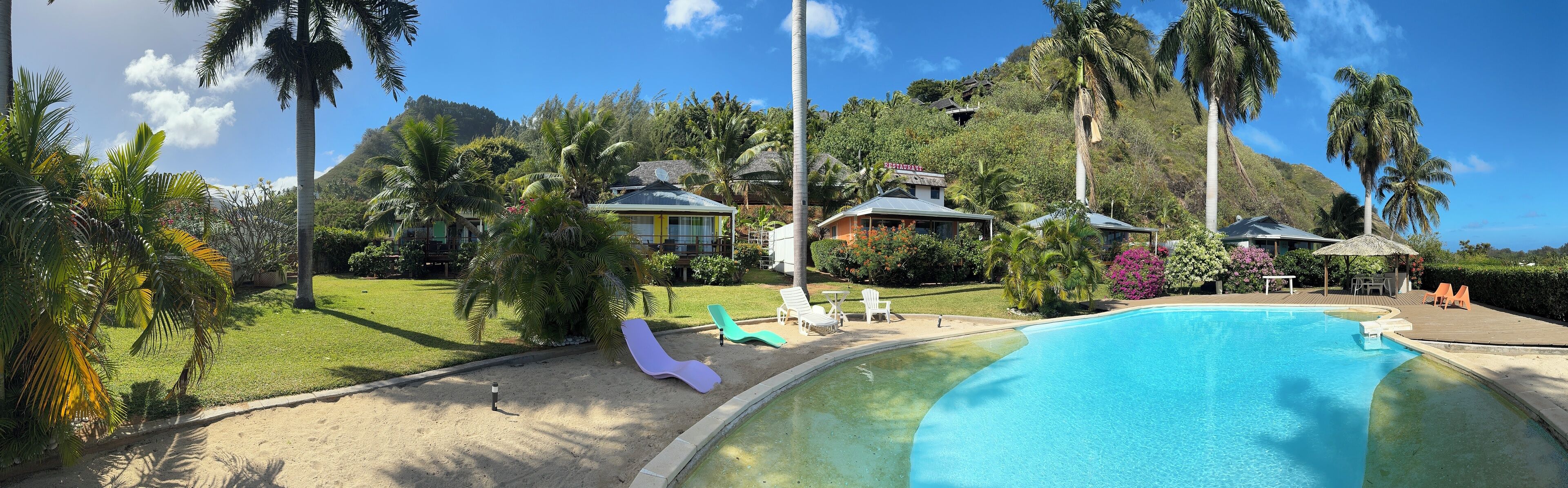 Un resort con piscina, sillas de descanso y restaurante.