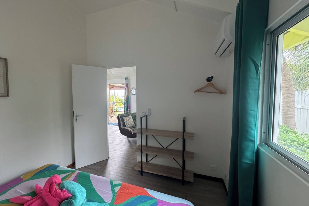 A room with a bed, a desk, a chair, and a window with curtains.