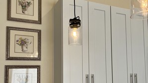 Une cuisine avec des armoires blanches, un luminaire suspendu et une enseigne « CUCINA » sur le comptoir.