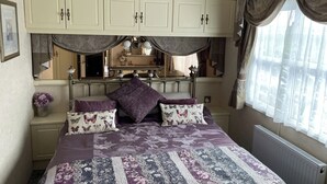 Une chambre à coucher avec un lit, une commode, un miroir et une fenêtre avec des rideaux.