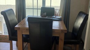 Un coin repas avec une table en bois et quatre chaises en cuir noir.