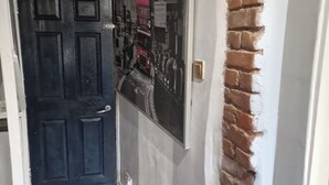 A hallway with a black door, a wall-mounted poster, and a brick accent wall.