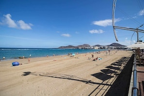 A beach with people, umbrellas, and a clear sky.