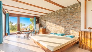 A bedroom with a large bed, wooden beams, a stone wall, and a view of the outdoors. - Vineyard House Marijan w/ Panoramic Views, Ljutomer, Slovenia (Ljutomer)