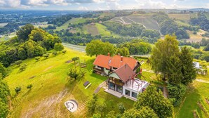 A house with a red roof, surrounded by lush green fields and trees, with a clear sky above. - Vineyard House Marijan w/ Panoramic Views, Ljutomer, Slovenia (Ljutomer)