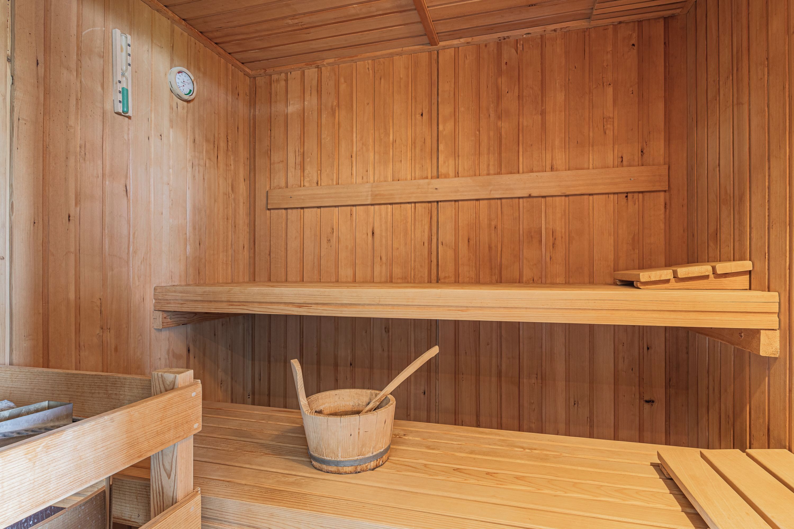 Un sauna en bois avec un banc en bois, un seau en bois et une étagère.