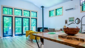 A spacious living area with large windows, a wooden floor, and a central island with a large bowl.