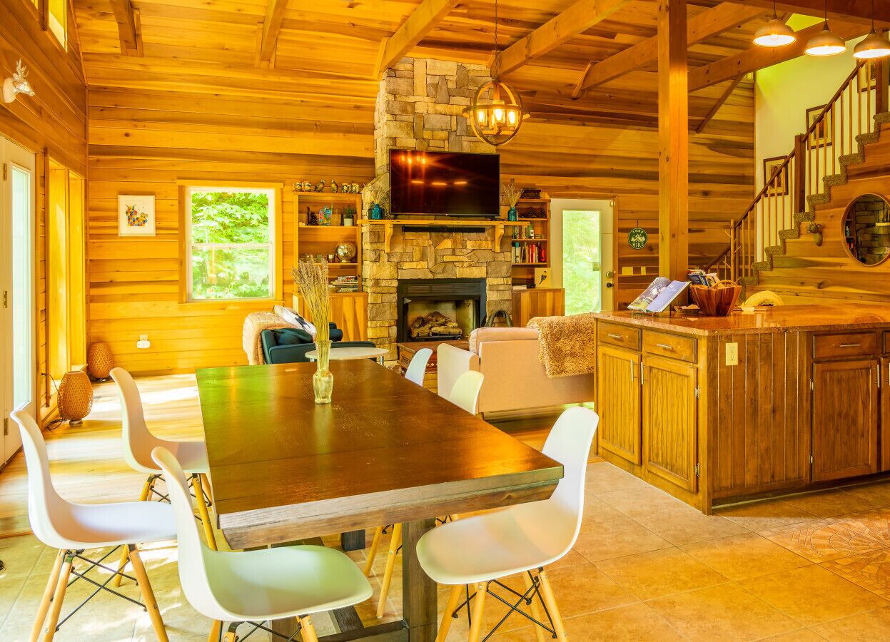 A cozy cabin interior with a dining area, kitchen, and living space.