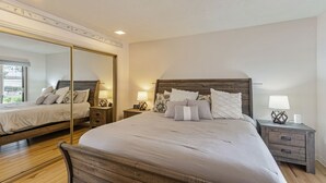Ein Schlafzimmer mit einem großen Bett, zwei Nachttischen, einem Spiegel und Holzboden.